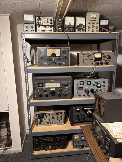 Uncle Bob's shack: five shelves of radios and test equipment, floor to ceiling